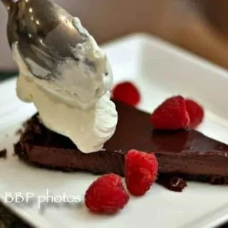 Easy, Luscious, Chocolate Glazed Chocolate Tart, served with Raspberries and Whipped Cream: the perfect dessert for entertaining. #chocolate #chocolatedessert #easychocolatedessert #Valentinesday
