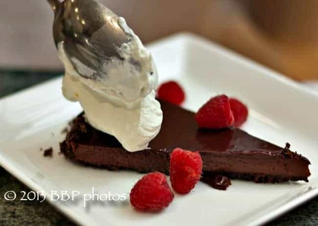 Easy, Luscious, Chocolate Glazed Chocolate Tart, served with Raspberries and Whipped Cream: the perfect dessert for entertaining. #chocolate #chocolatedessert #easychocolatedessert #Valentinesday