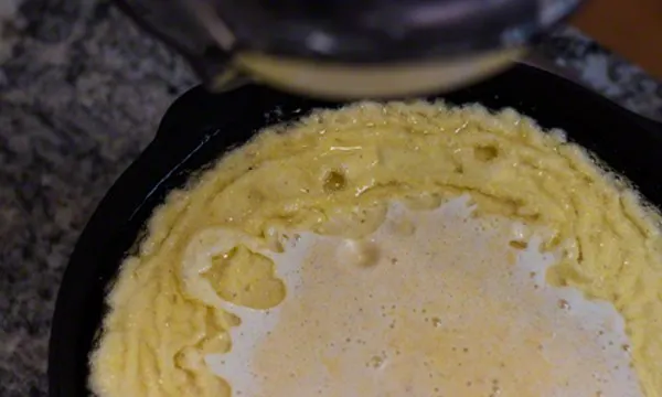 Adding batter into skillet. The hot oil that is in the skillet will sizzle around the edges.