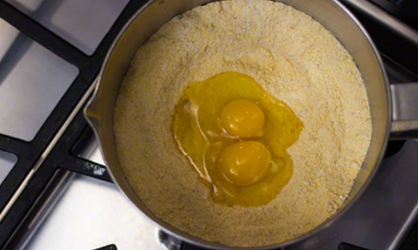 Eggs that have been cracked into the well in the cornmeal.