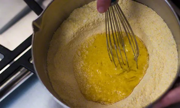 Mixing eggs in well of dry ingredients.