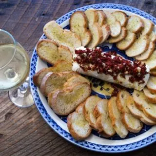 A Thanksgiving appetizer that's quick, easy, beautiful, and amazingly delicious! Goat Cheese with Sun-Dried Tomatoes, Garlic, and Rosemary on Crostini. Perfect for Christmas parties, too! #Thanksgiving #appetizer #holiday #cheese #chevre #goatcheese #cheeseball