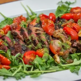 Grilled Marinated Flank Steak with Blistered Tomatoes and Basil Vinaigrette is the perfect meal for easy entertaining. #steak #flanksteak #grilling #tomatoes #arugula
