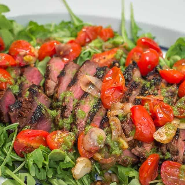 Grilled Marinated Flank Steak with Blistered Tomatoes and Basil Vinaigrette is the perfect meal for easy entertaining. #steak #flanksteak #grilling #tomatoes #arugula