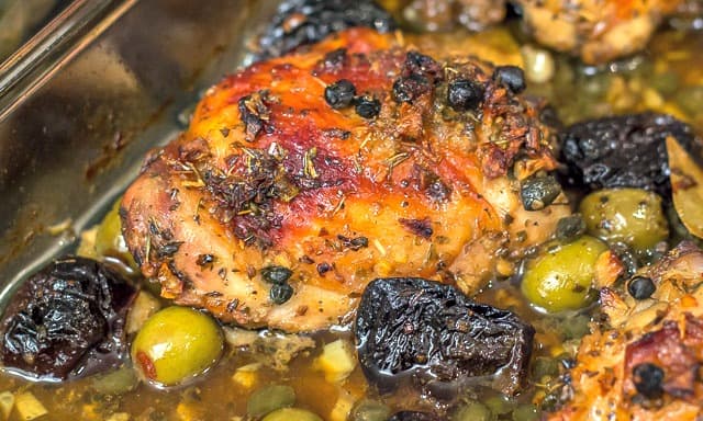 Chicken Marbella, a classic dish, is chicken roasted with garlic, olives, capers, and prunes. It's the perfect meal for a large dinner party. #dinnerparty #chicken #chickenrecipe