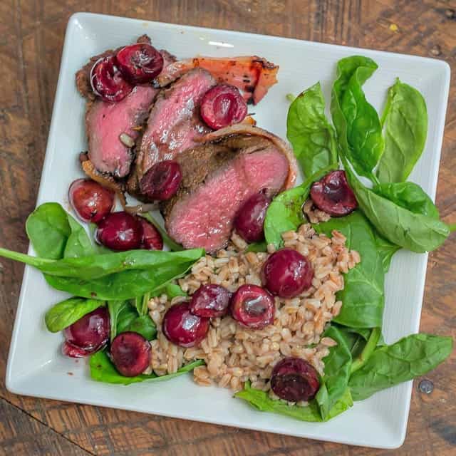 Easy, yet delicious enough for a gourmet palate: Grilled Bacon-Wrapped Venison Backstrap with Balsamic Cherries and Farro #grilling #venison #tenderloin #backstrap #baconwrappedvenison