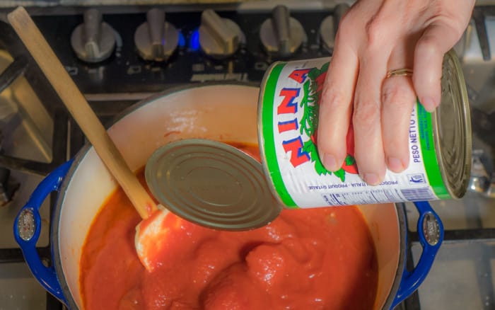 Pouring canned tomatoes into pot