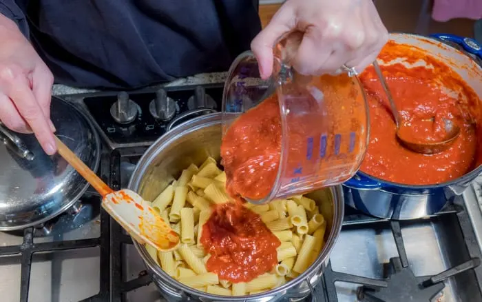 Pouring the sauce over the pasta.