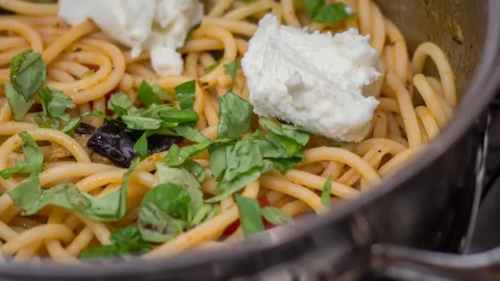 Adding fresh ricotta and basil to the Pasta Alla Norma