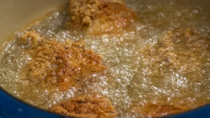 The chicken needs to cook covered in the Dutch oven for 10 minutes. Then, you fry until it's golden brown, and remove it from the oil, where you check to make sure it has reached 160º.