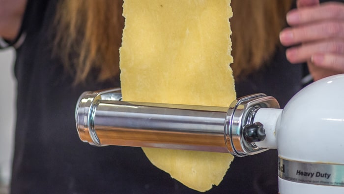 After rolling one fourth of your dough into a rectangular shape with a rolling pin, you feed the dough through the widest setting of the roller attachment. 