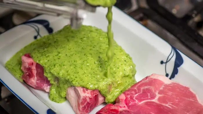 Pouring the marinade over the raw pork chops, so they can enjoy each other's company for an hour in the fridge.