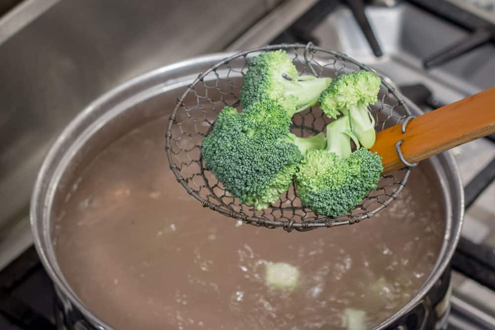 Dropping the broccoli into the boiling salted water.