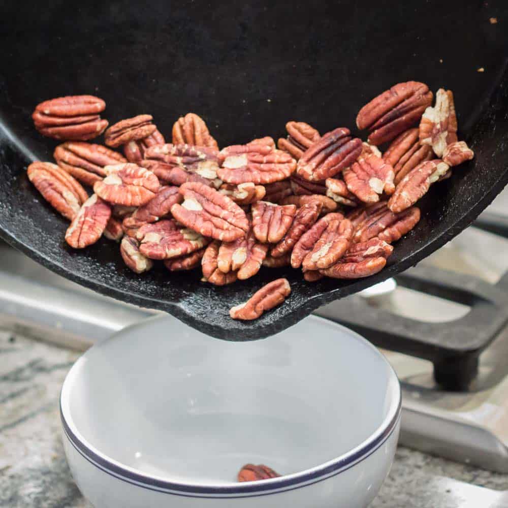 Toasting the pecans in a cast iron skillet.