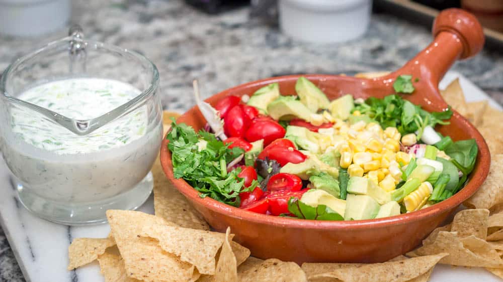 A picture of the chopped salad with the dressing and the chips on the side.