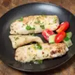 Permalink to: Easy Walleye Meunière Recipe Plated with a simple salad of cucumbers and tomatoes.