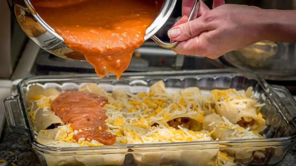 Pouring the sauce over the stuffed enchilads.