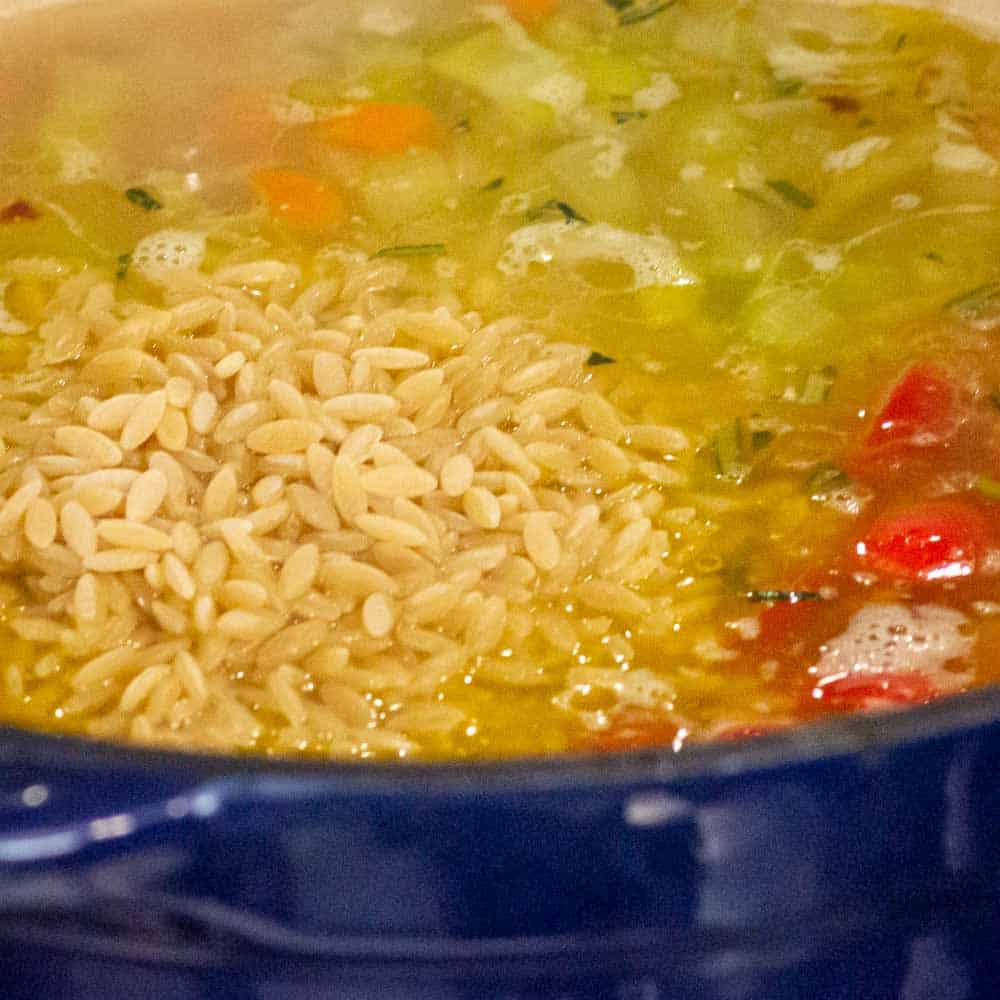 Adding the orzo to the soup.