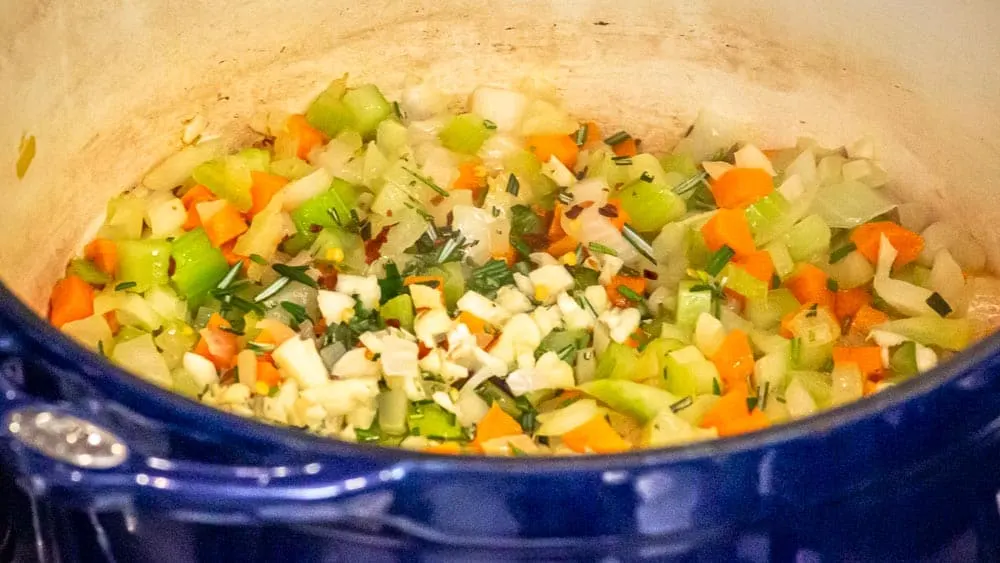 Adding rosemary to the simmering veggies.
