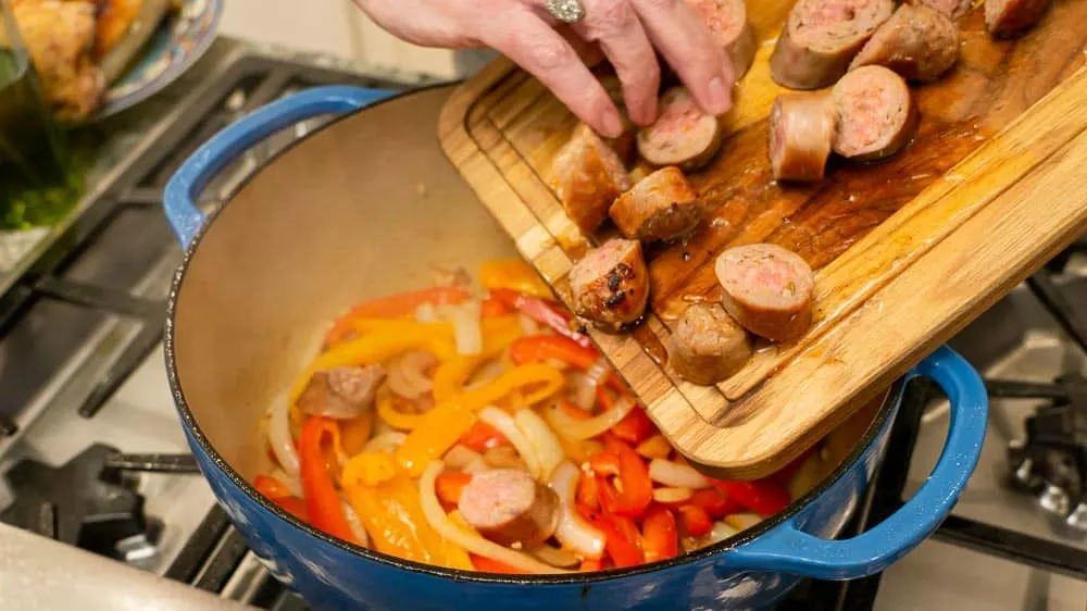 Adding the sausage chunks to the sautéd veggies.