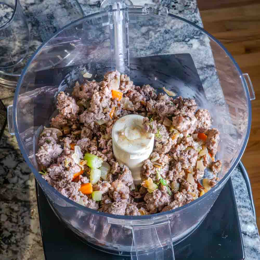 Pouring the meat mixture into the food processor.