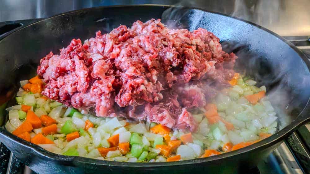 Adding the meat mixture to the veggie mixture. 